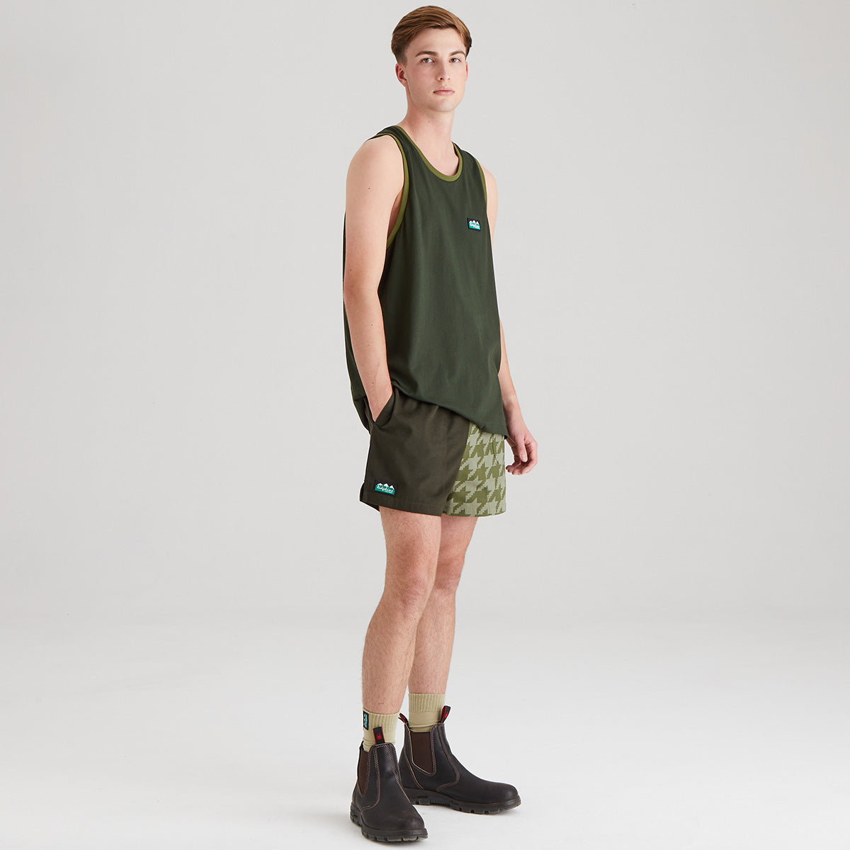 Person wearing a green tank top and shorts on a white background