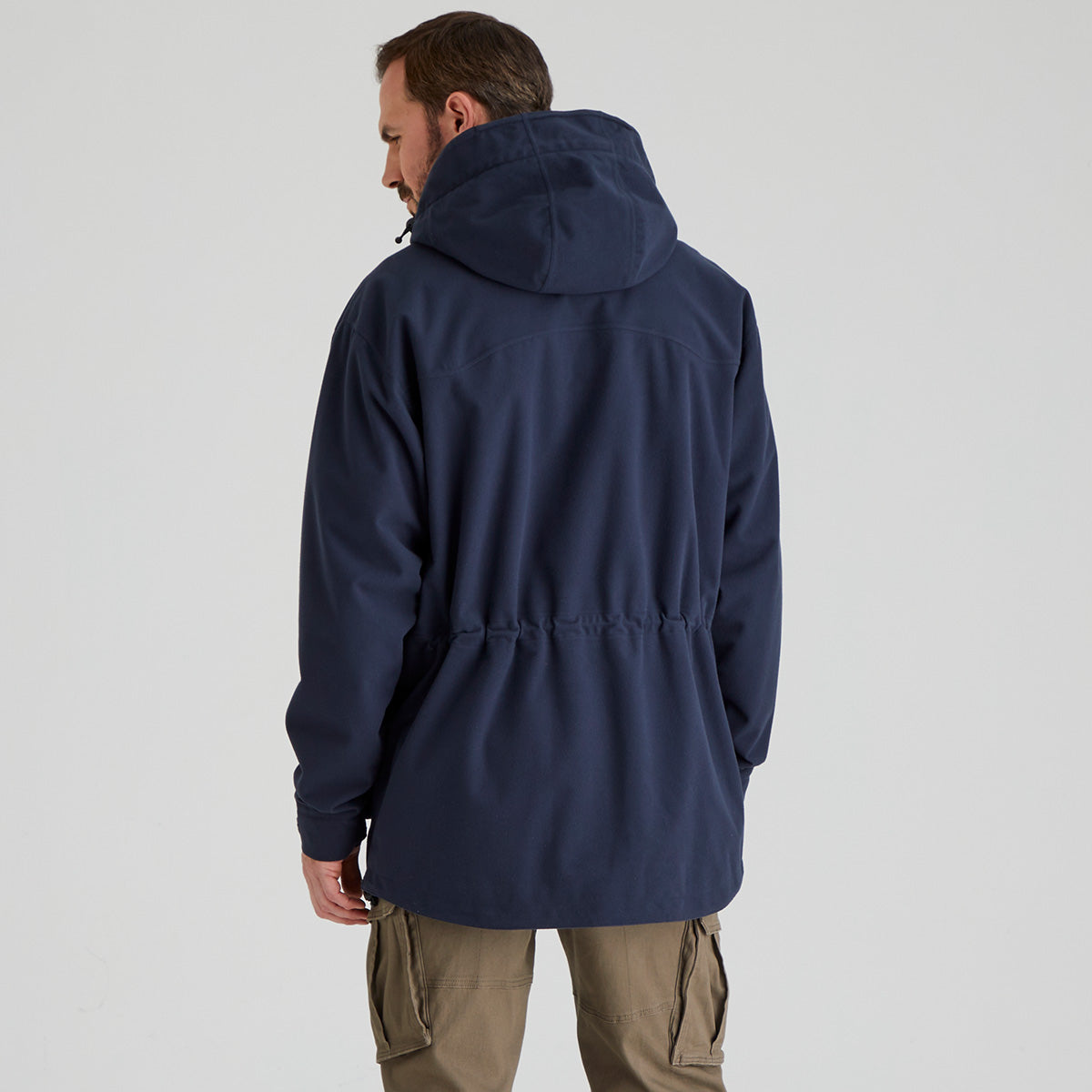 back view of man wearing a navy blue hooded jacket on a light grey background