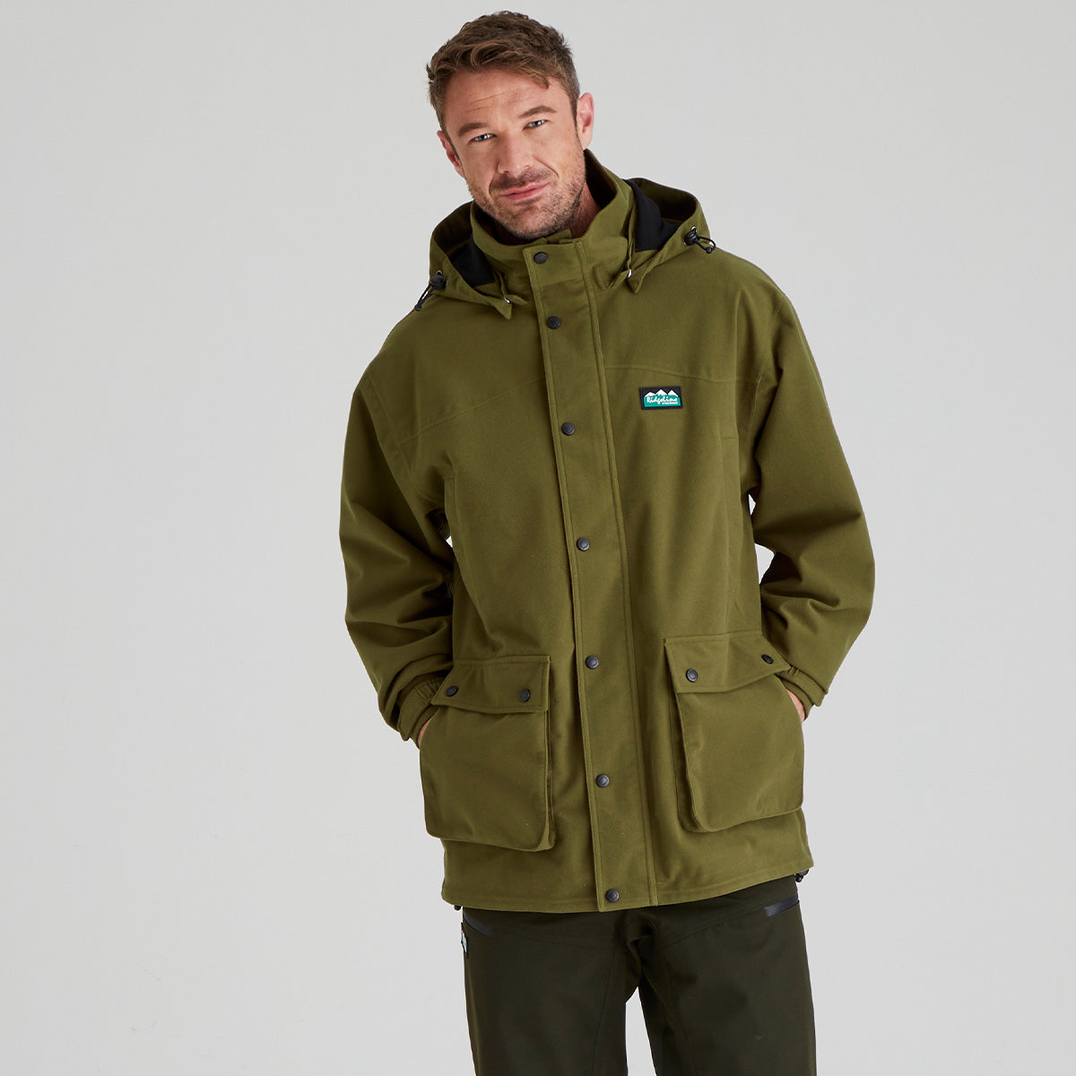 Man wearing a brown waterproof jacket with a visible Ridgeline Clothing brand logo on a grey background