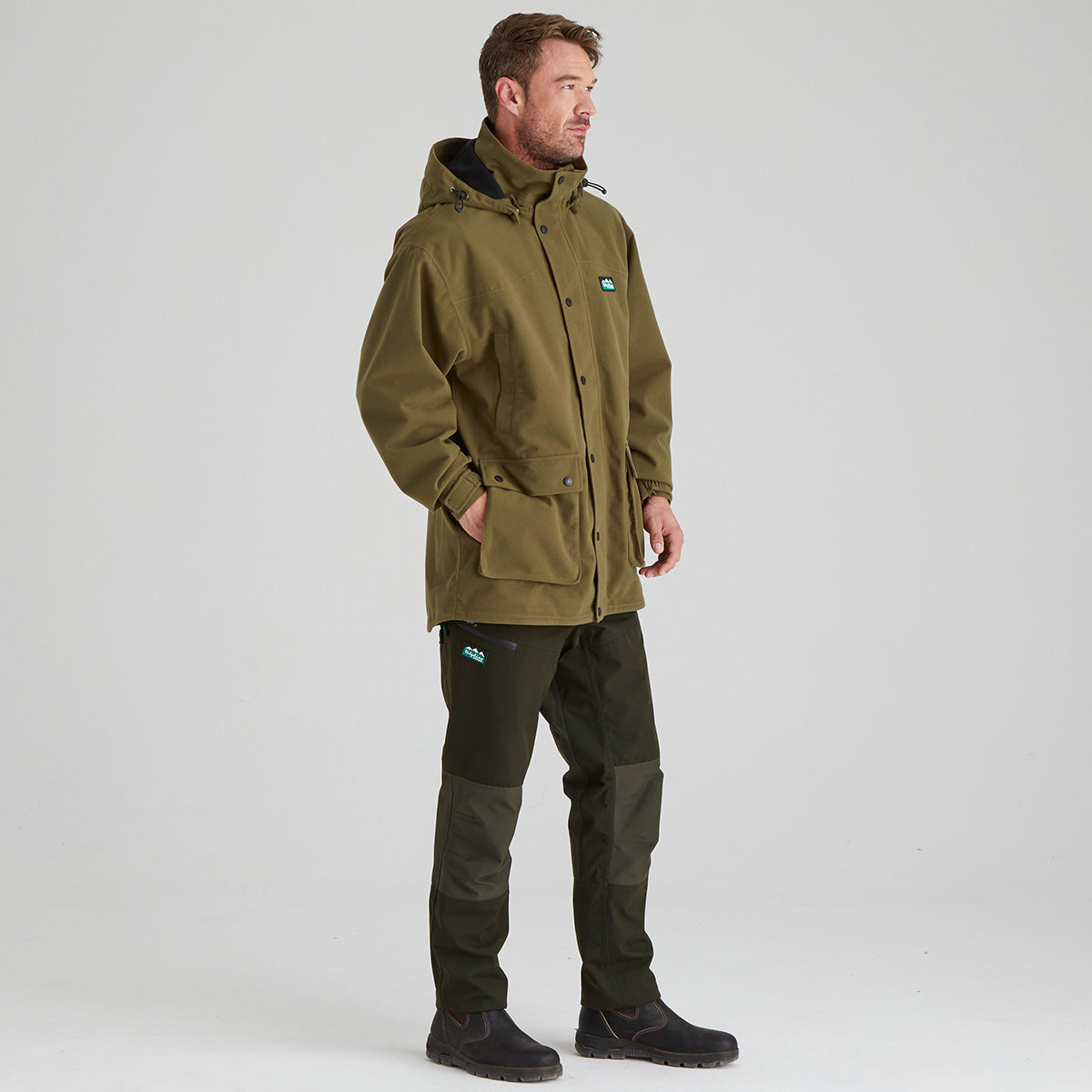 Man wearing a green jacket and pants on a white background