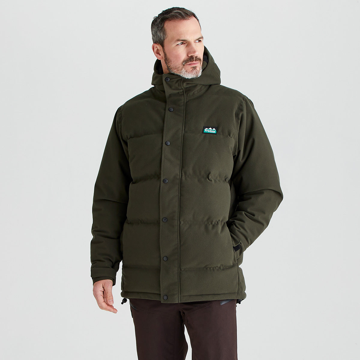 Man wearing a green jacket with a logo on a light gray background