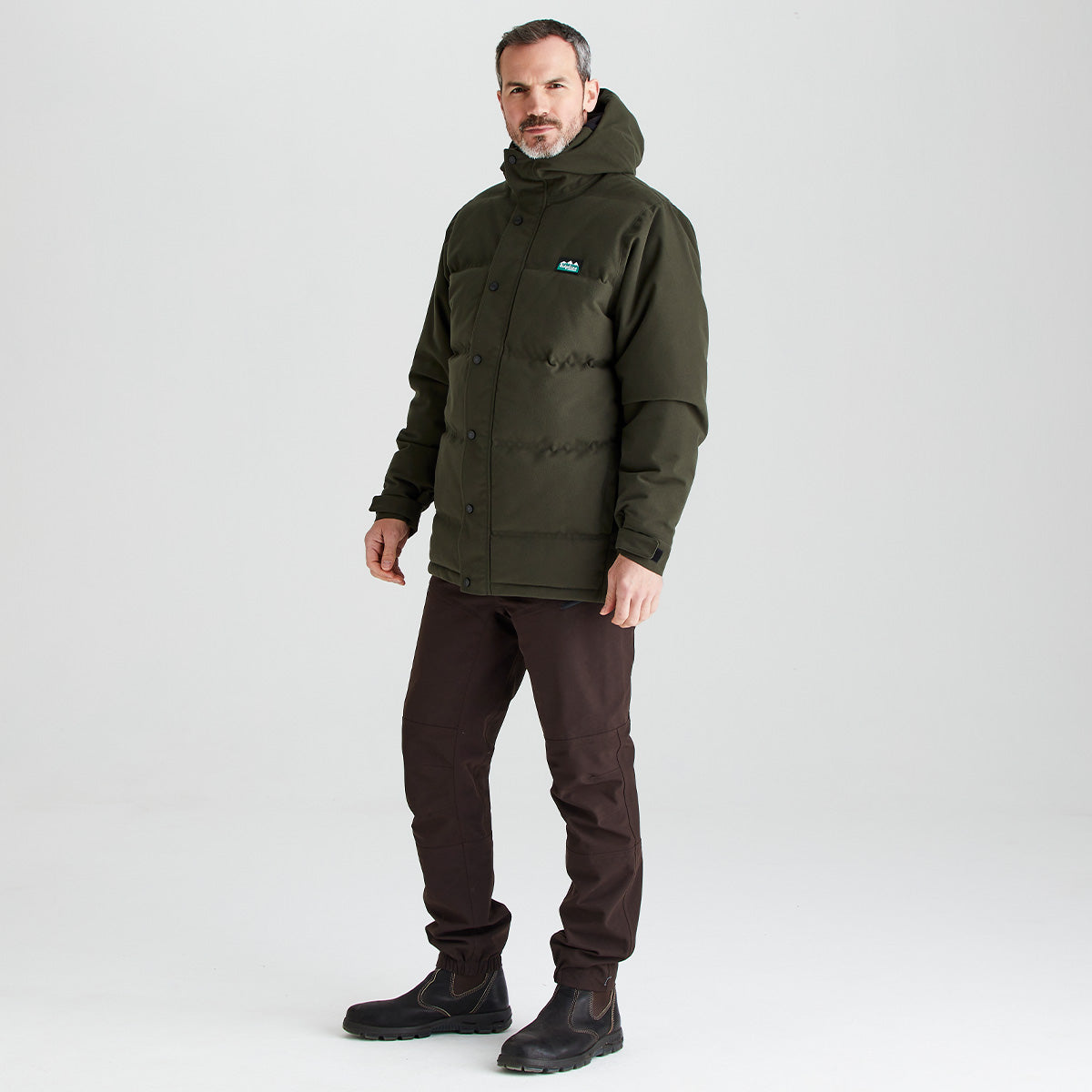Man wearing a green jacket with a brand logo on a white background