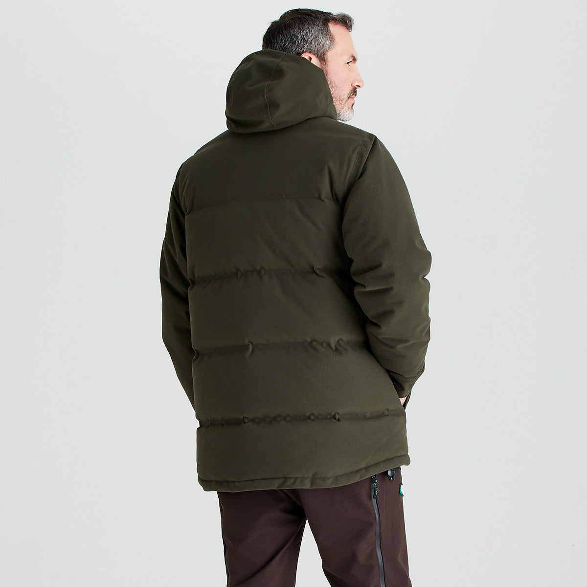 Man wearing a green puffer jacket on a light gray background