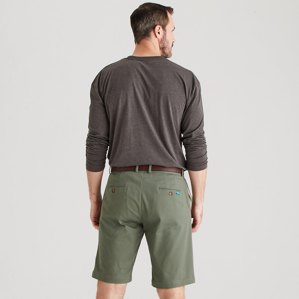 Man wearing a gray long-sleeve shirt and green shorts on a light gray background