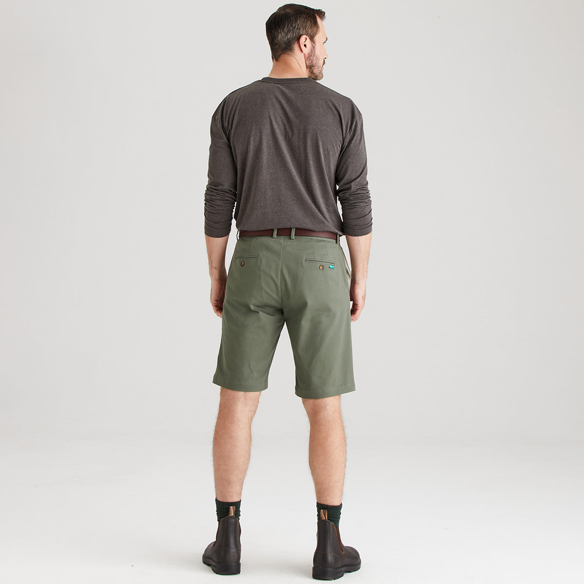 Man wearing green shorts and a gray shirt on a white background