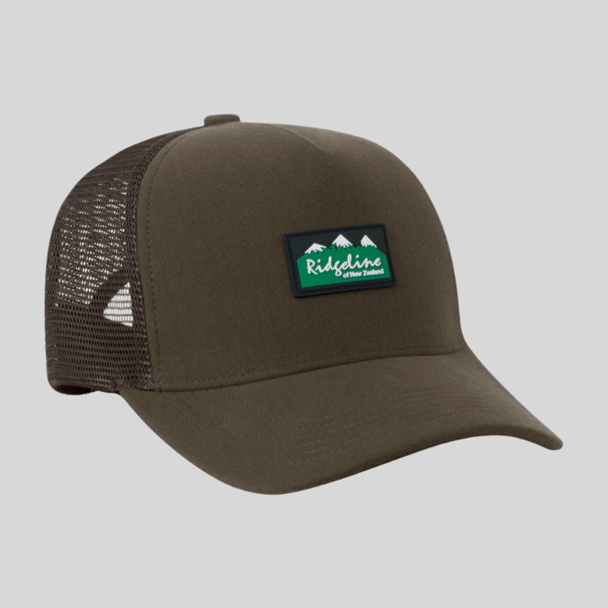 A brown Monsoon trucker cap with breathable mesh panels and an adjustable back, featuring a waterproof peak.