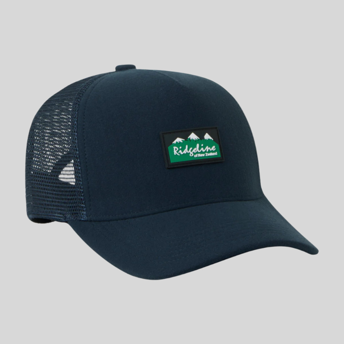 A green Monsoon trucker cap with breathable mesh panels and an adjustable back, featuring a waterproof peak.