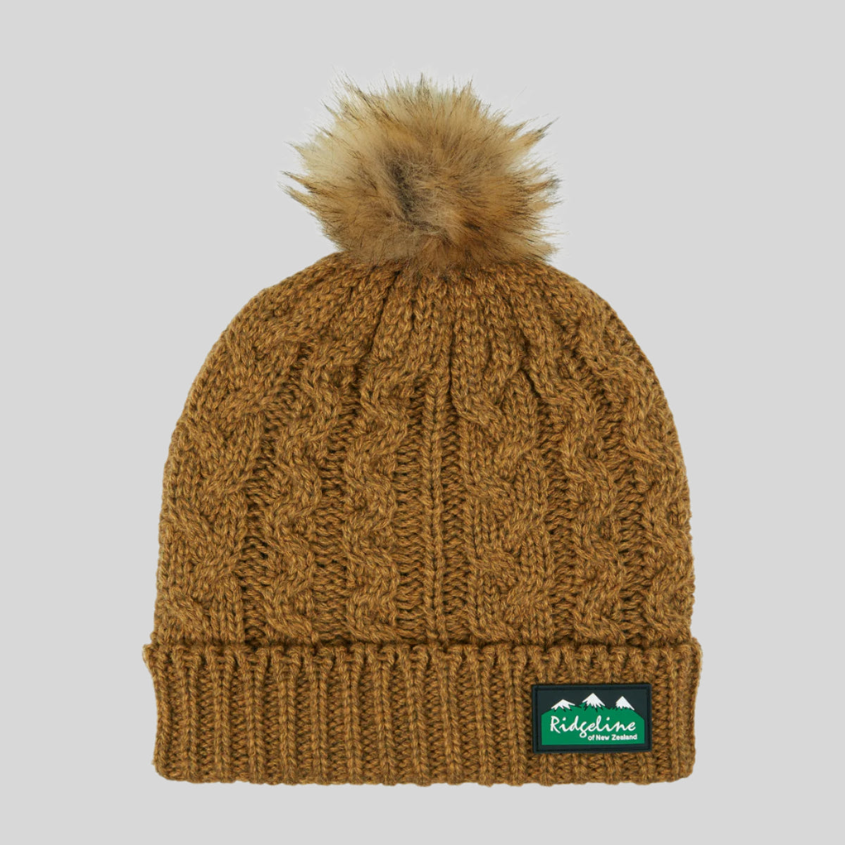 A brown Nordic Fleck bobble hat with a white pom-pom on top and a wide rib turn-up band. on a white background