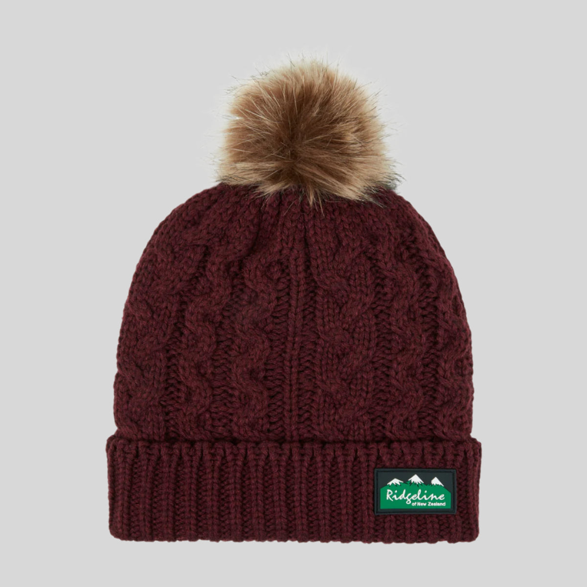 A red Nordic Fleck bobble hat with a white pom-pom on top and a wide rib turn-up band. on a white background
