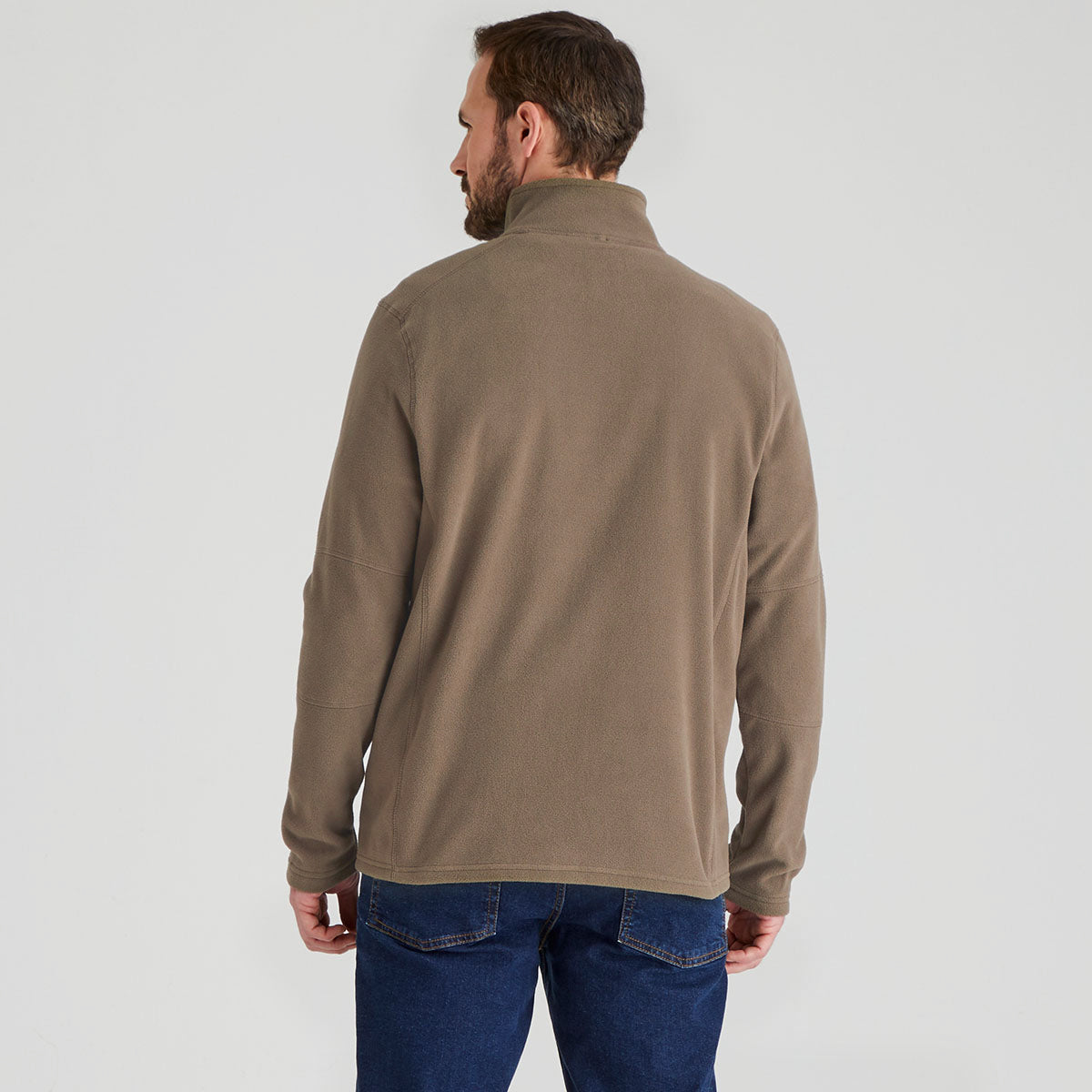 Man wearing a brown fleece pullover and blue jeans on a white background