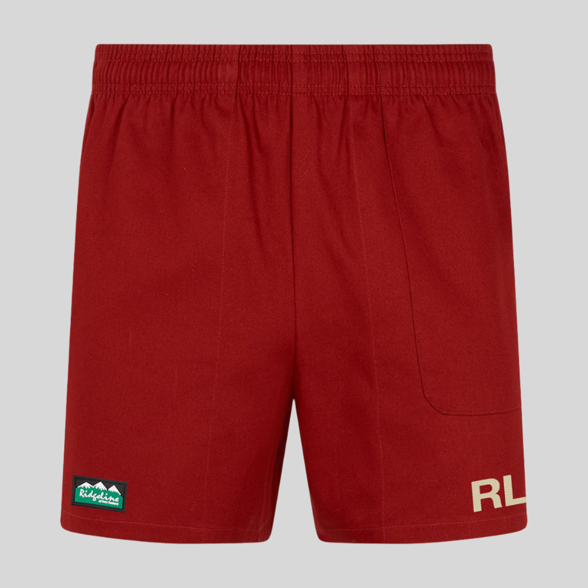 A pair of red rugby shorts with a visible Ridgeline brand logo on the left leg and a small RLNZ badge on the right pocket.