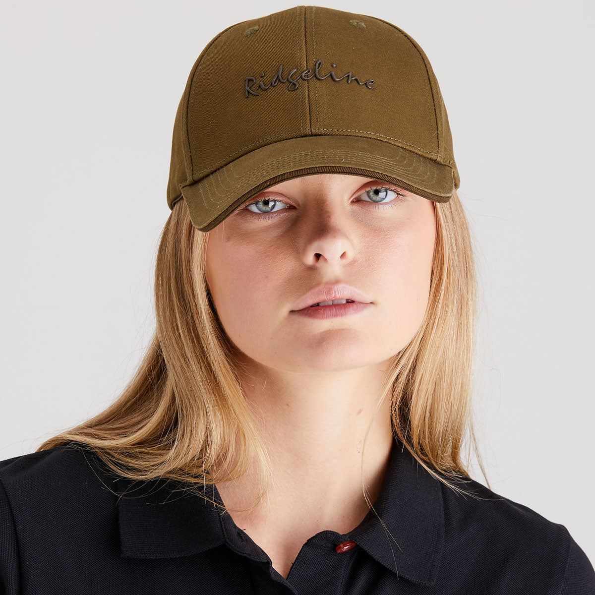 Person wearing a brown cap with 'Ridgeline' embroidery on a plain background