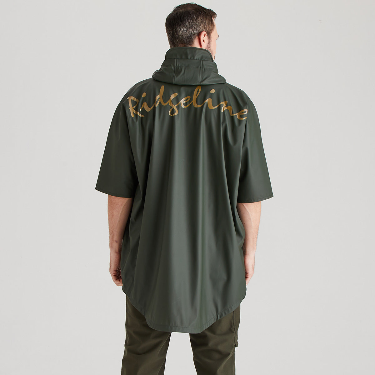 Person wearing a green raincoat with 'Ridgeline' branding on the back against a gray background