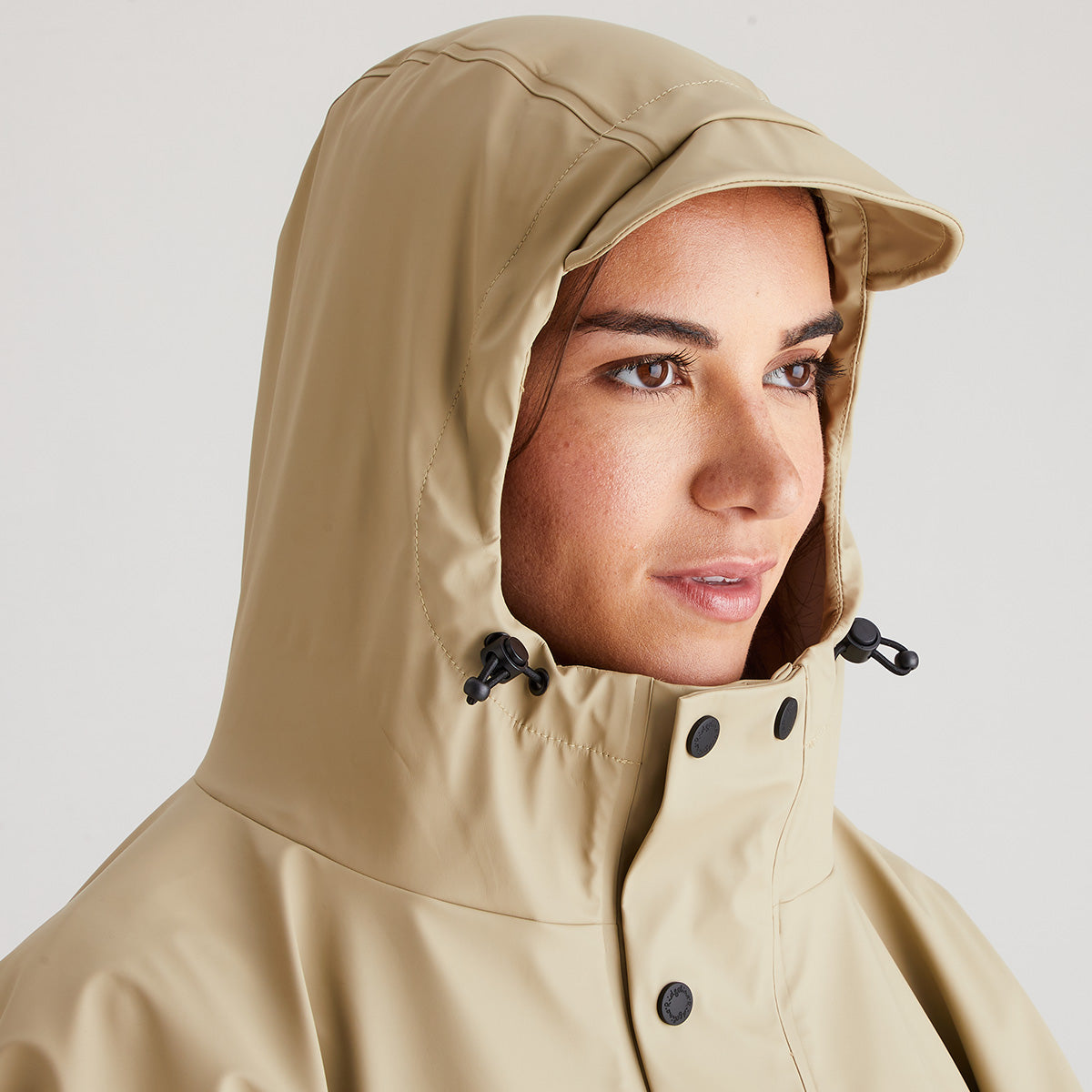 Person wearing a beige hooded jacket on a plain background