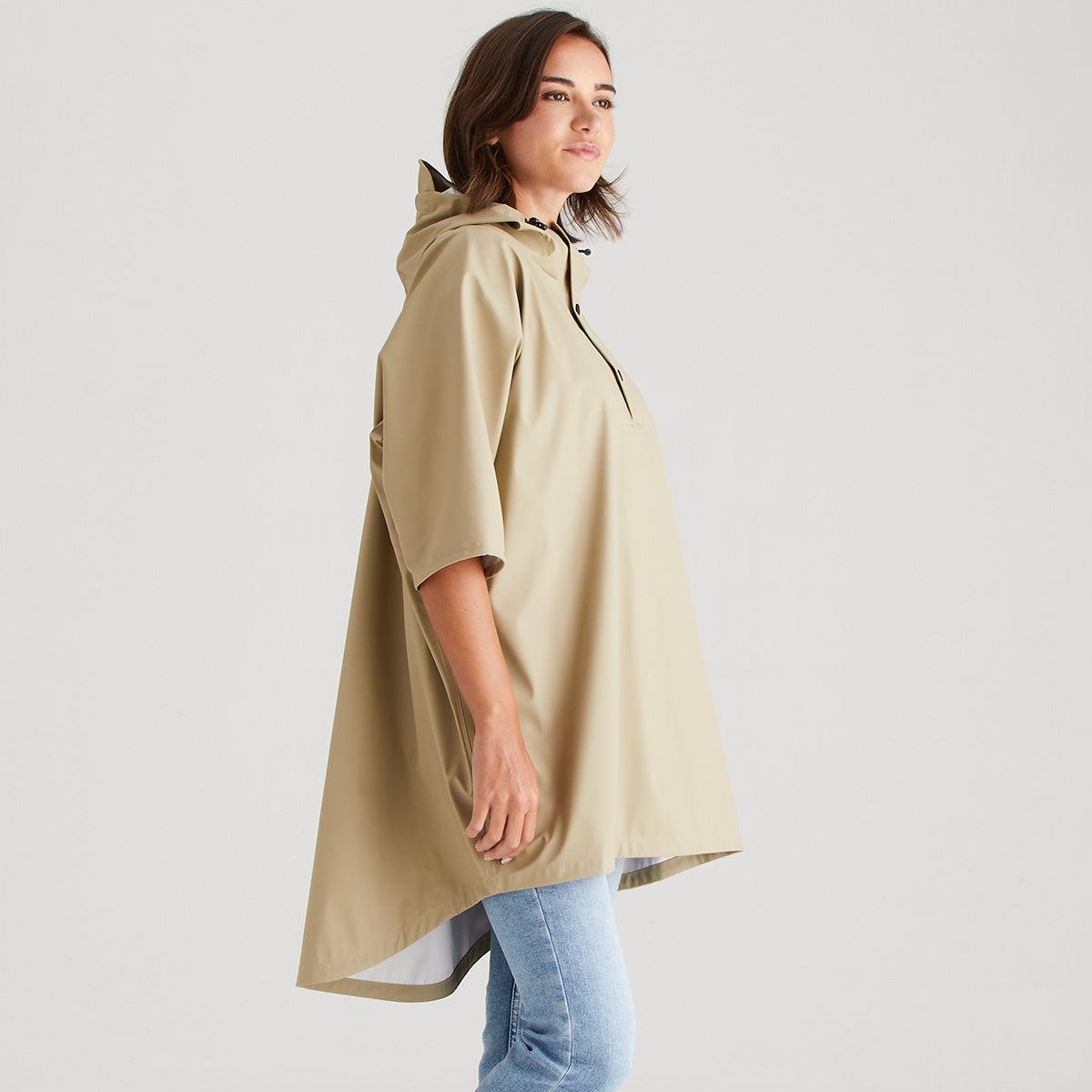 Woman wearing a beige raincoat against a plain background
