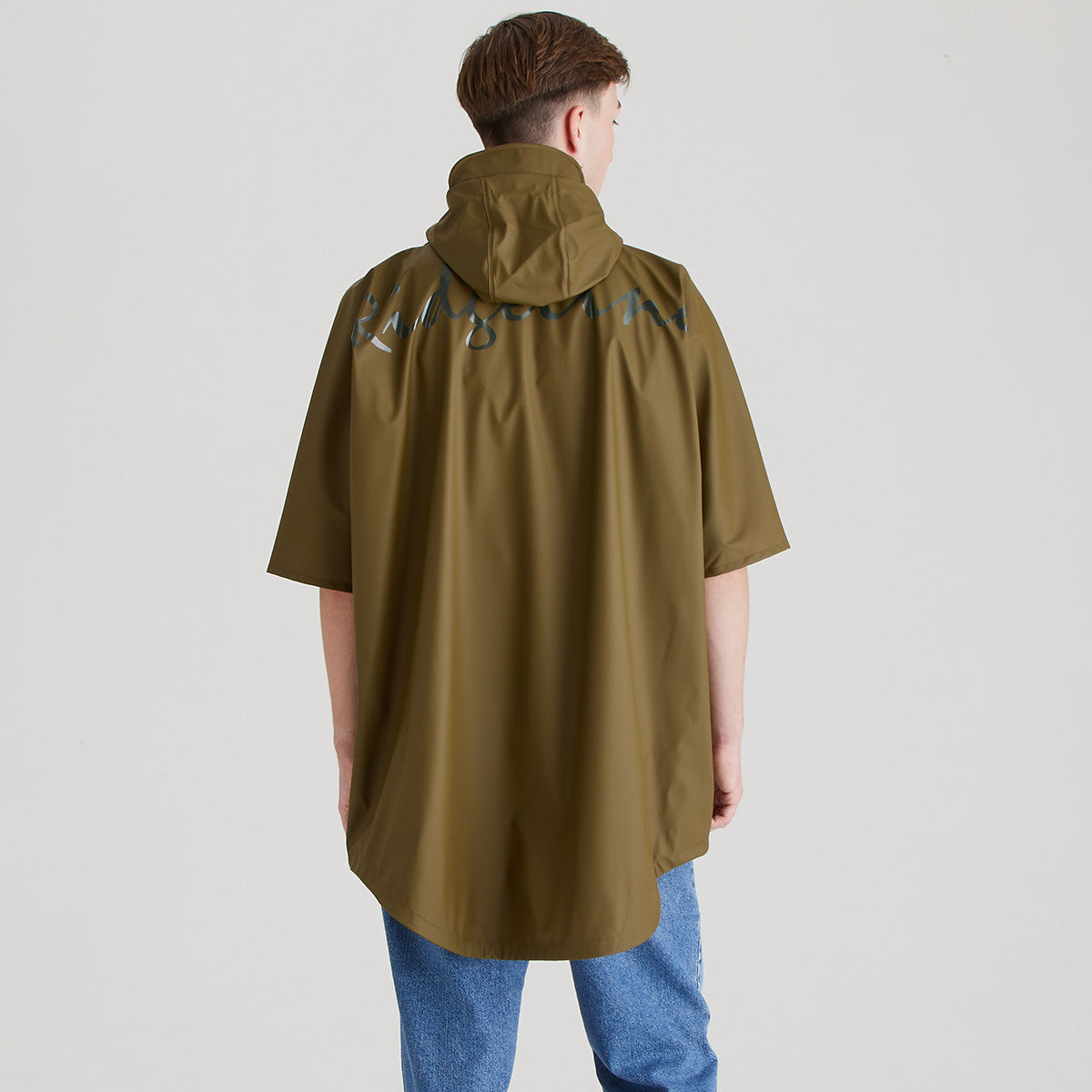 Person wearing a brown raincoat with branding on the back against a plain background
