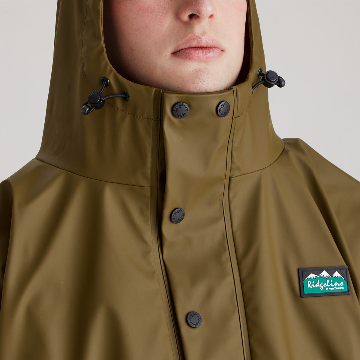 Brown raincoat with a visible brand logo on a neutral background