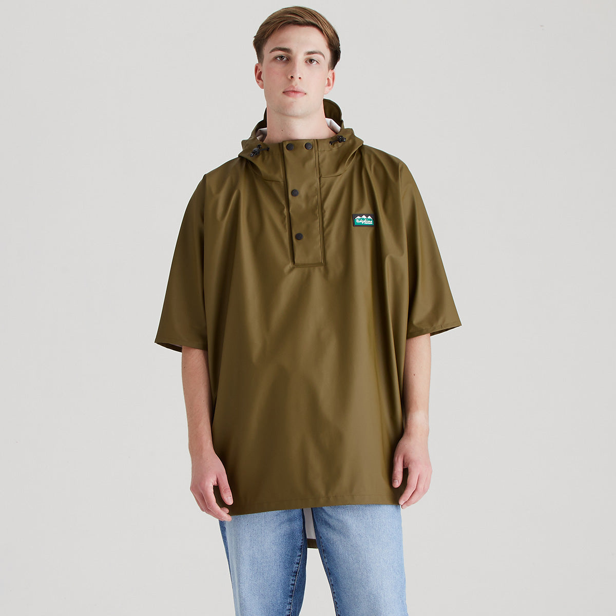 Person wearing a teak rain poncho on a plain background