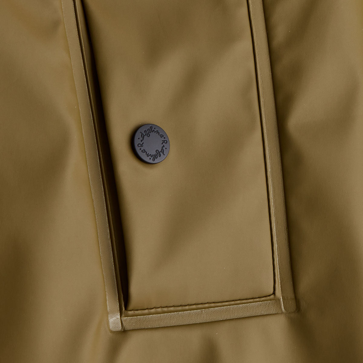 Close-up of a beige jacket with a button on a matching background