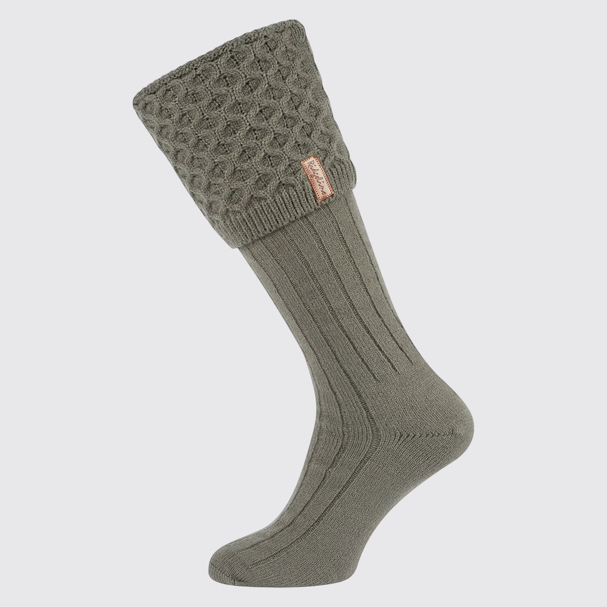Single olive-green welly sock with a long ribbed leg and a chunky cable-knit turnover cuff, displayed against a light grey background. The cuff features a textured cable-knit pattern and a small Ridgeline branded tag on the side. Designed to be worn with wellington boots, the sock combines a classic country look with a cosy, insulated feel for added warmth and comfort in cold weather.
