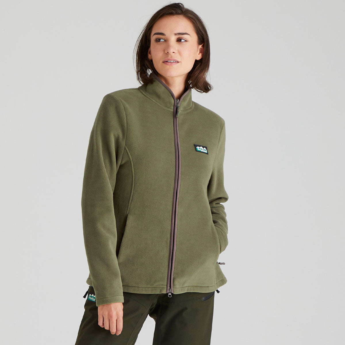 Person wearing a green fleece jacket with a brand logo on a grey background