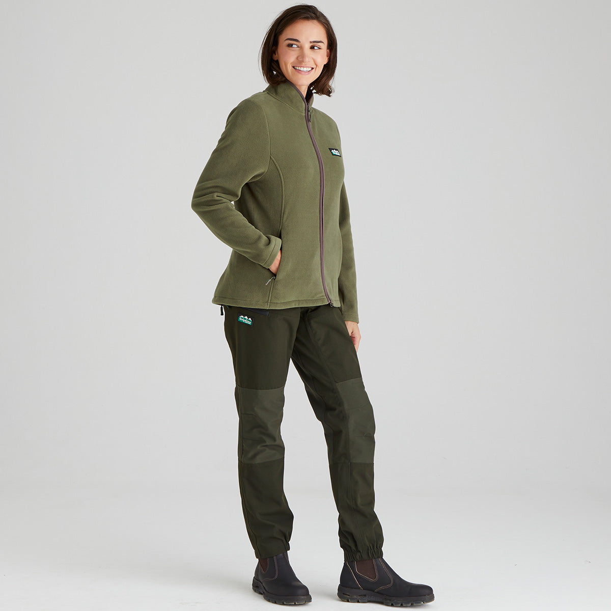 Person wearing a green fleece jacket and pants on a light grey background