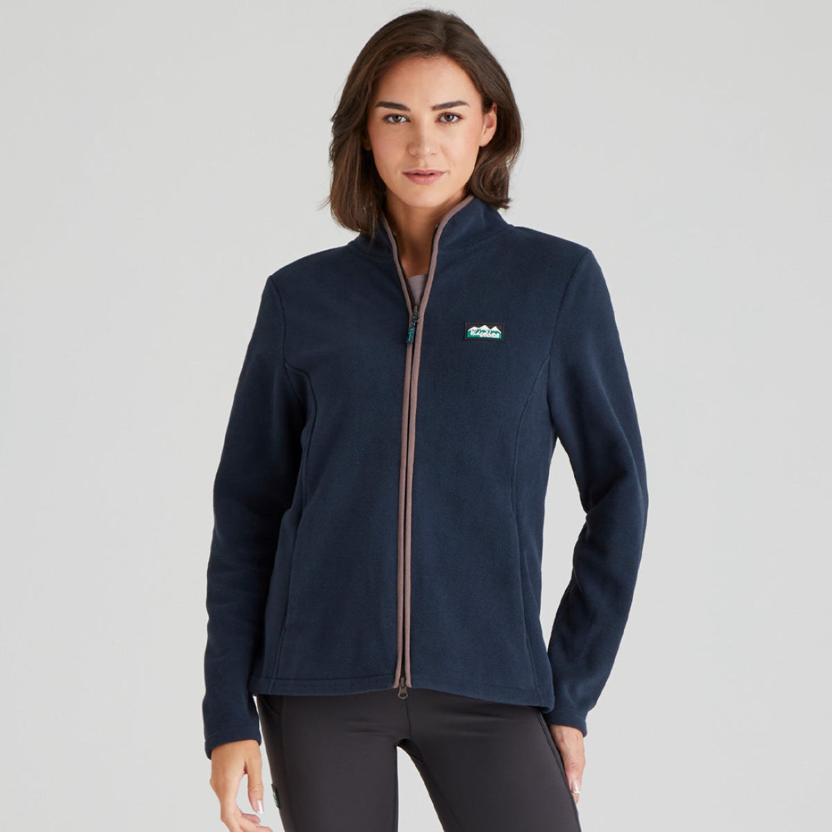 Woman wearing a navy blue full zip Fleece jacket with a Ridgeline Clothing brand logo on a grey background