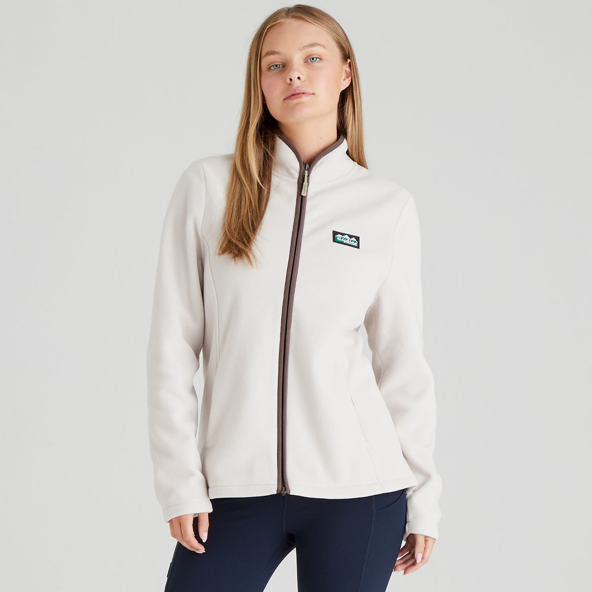 Person wearing a white full zip fleece jacket, navy leggings, on a light grey background