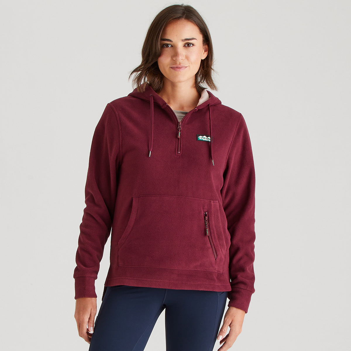 Woman wearing a maroon hoodie with a logo on a gray background