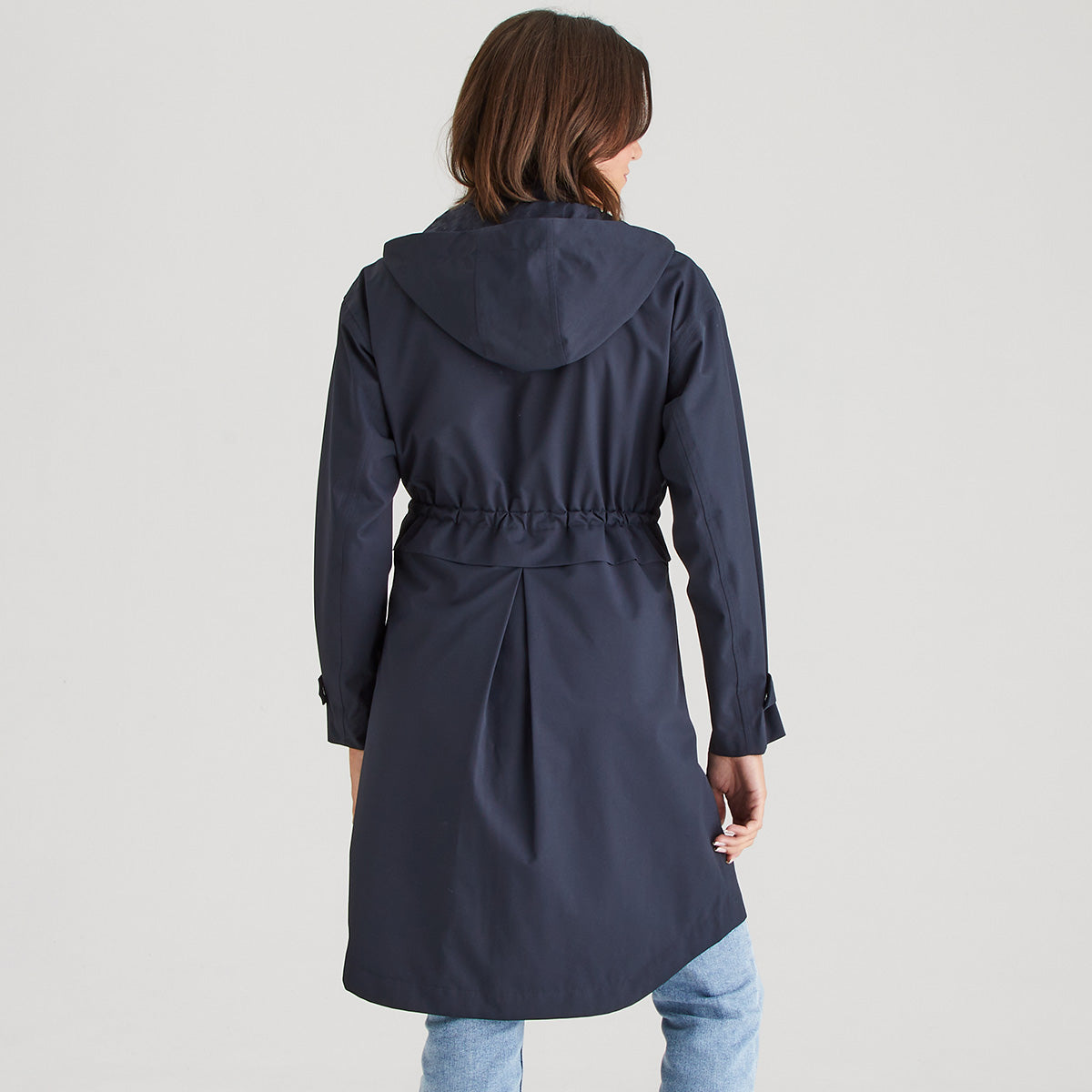Person wearing a navy blue raincoat on a light gray background