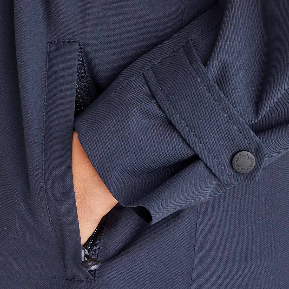 Close-up of a navy blue jacket with a button and zipper detail.