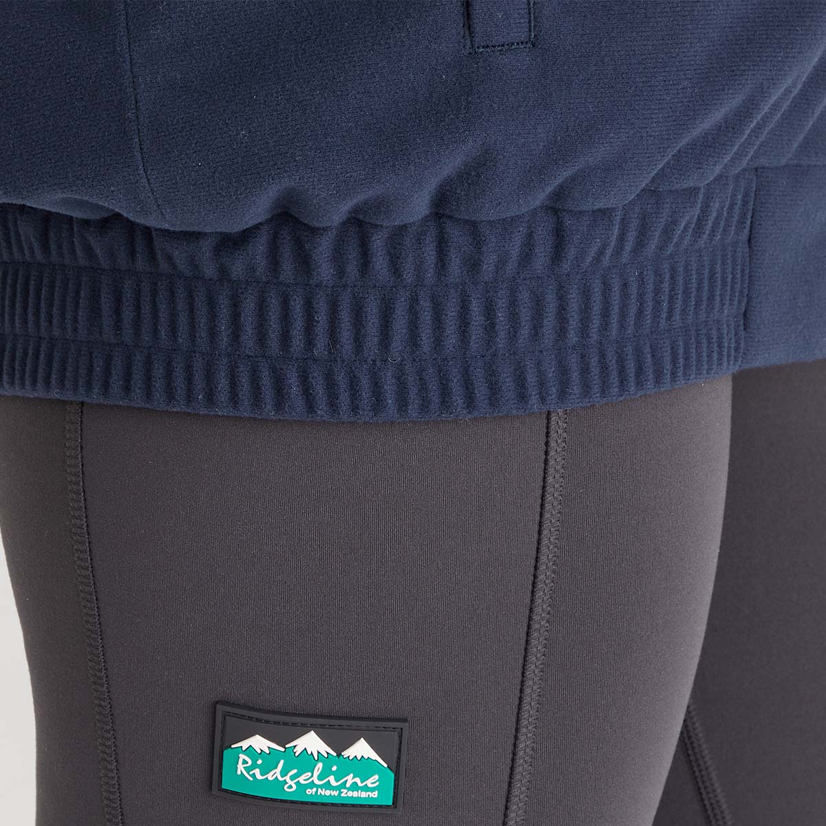 Navy sweater and gray pants with a visible brand logo on the pants.