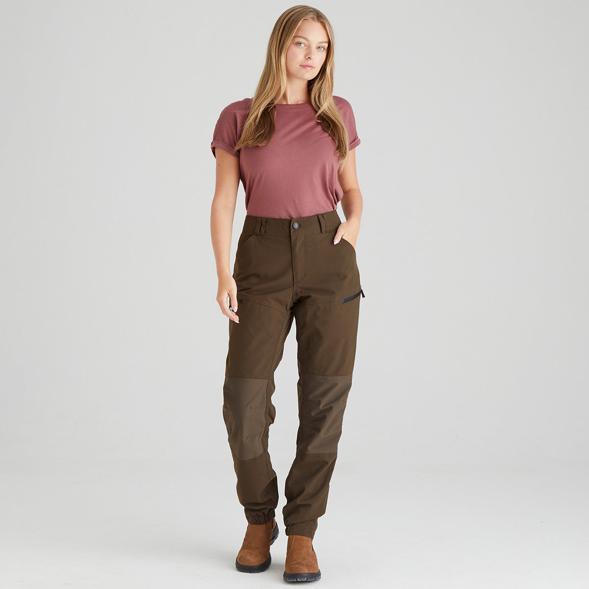 Woman wearing brown pants and a maroon shirt on a light gray background