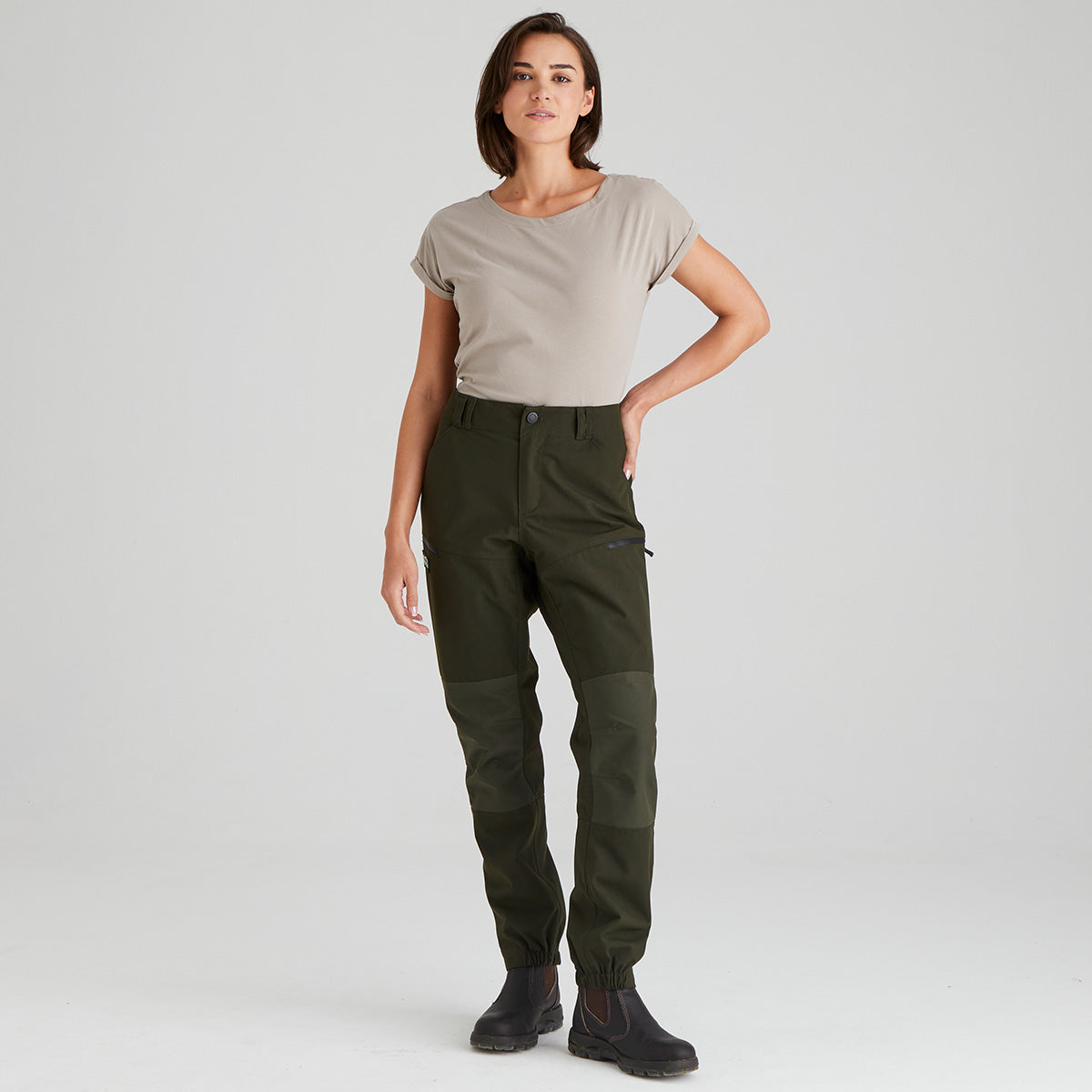 Woman wearing green pants and a beige shirt on a white background