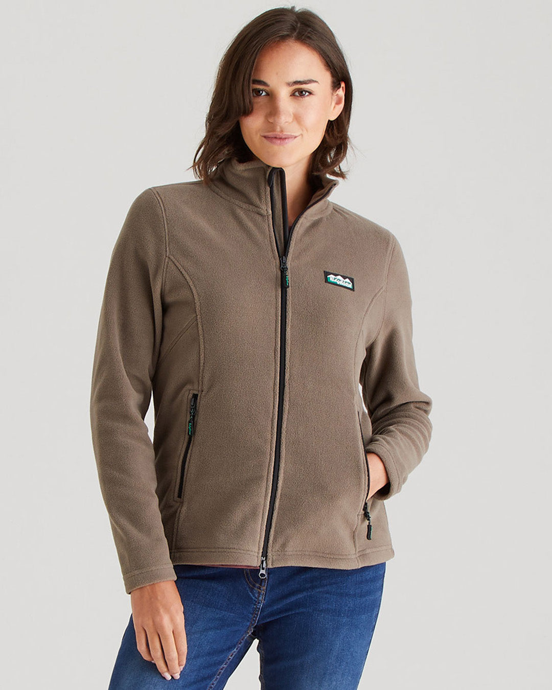 Woman wearing a brown jacket with a visible brand logo on a plain background