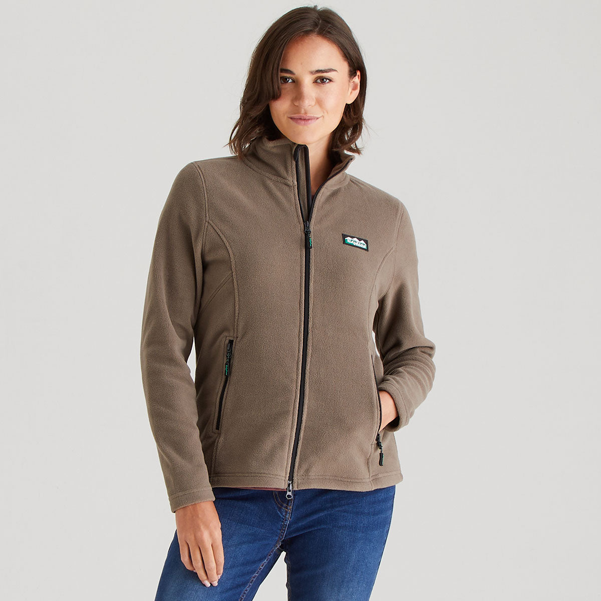 Woman wearing a brown jacket with a brand logo on a light gray background