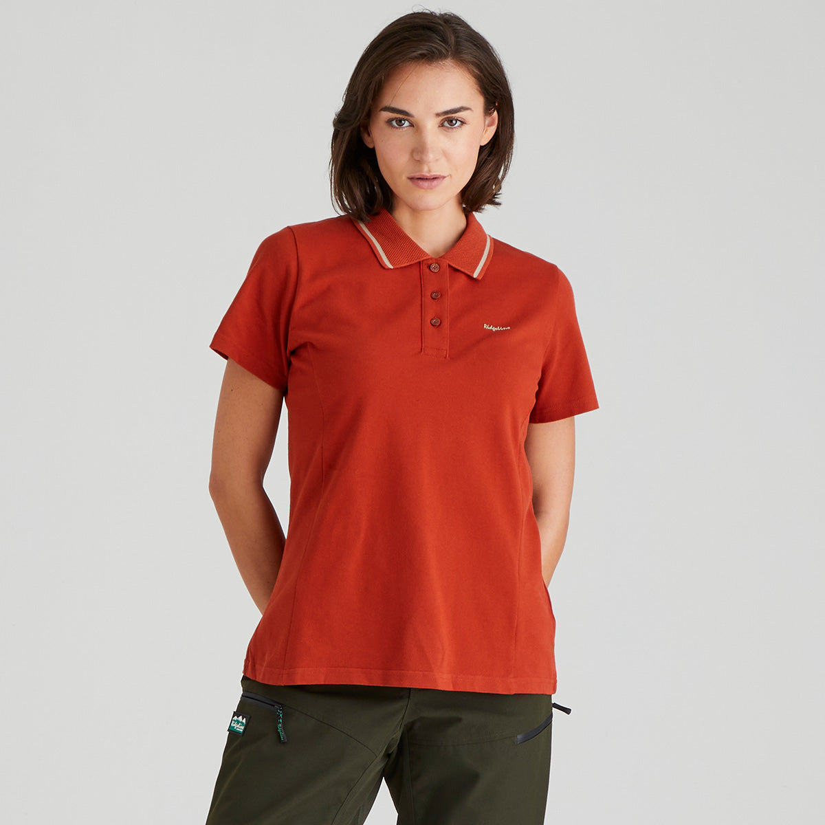 woman wearing a orange polo shirt with a ridgeline clothing logo on a grey background