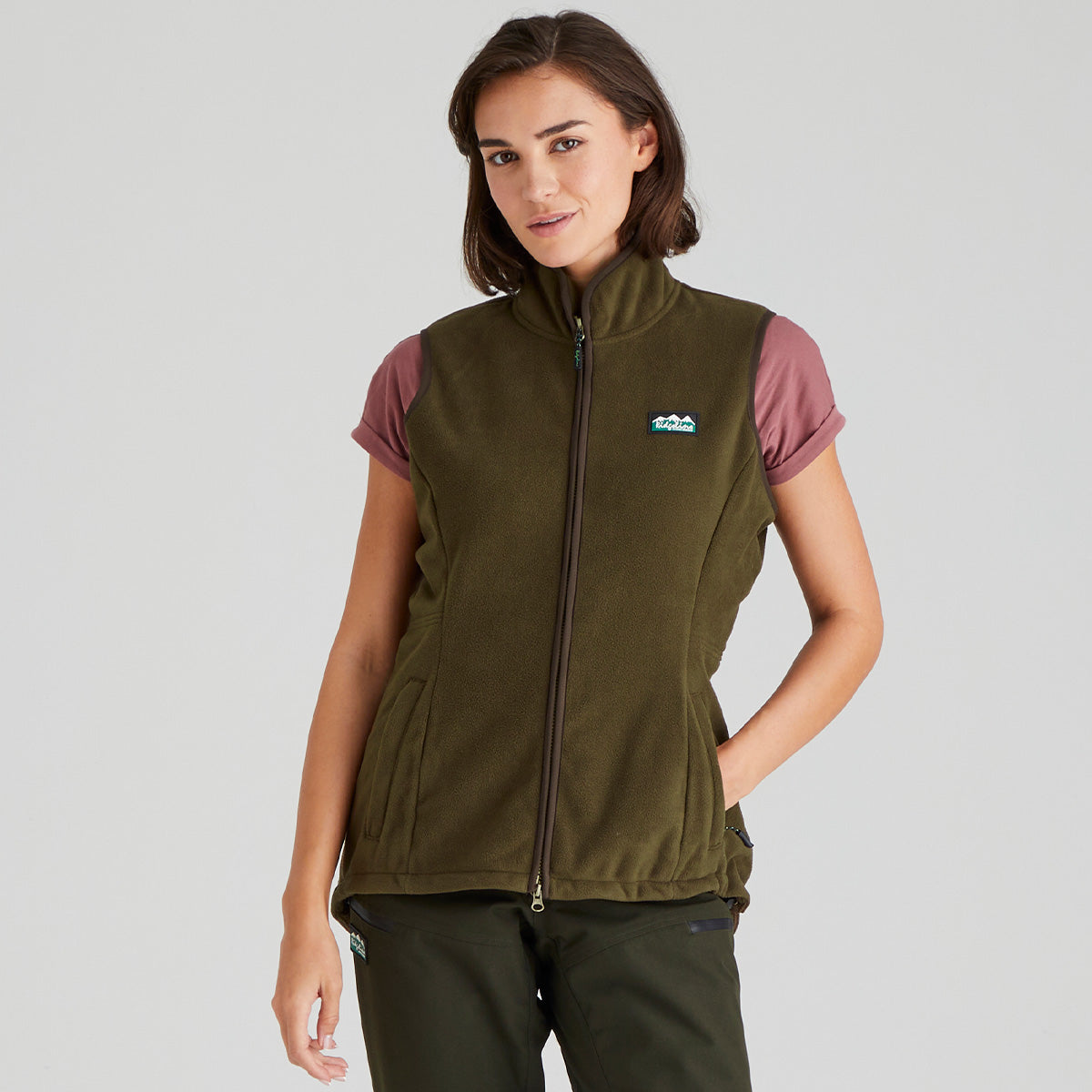 Woman wearing a brown fleece gilet with a Ridgeline Clothing logo on a grey background