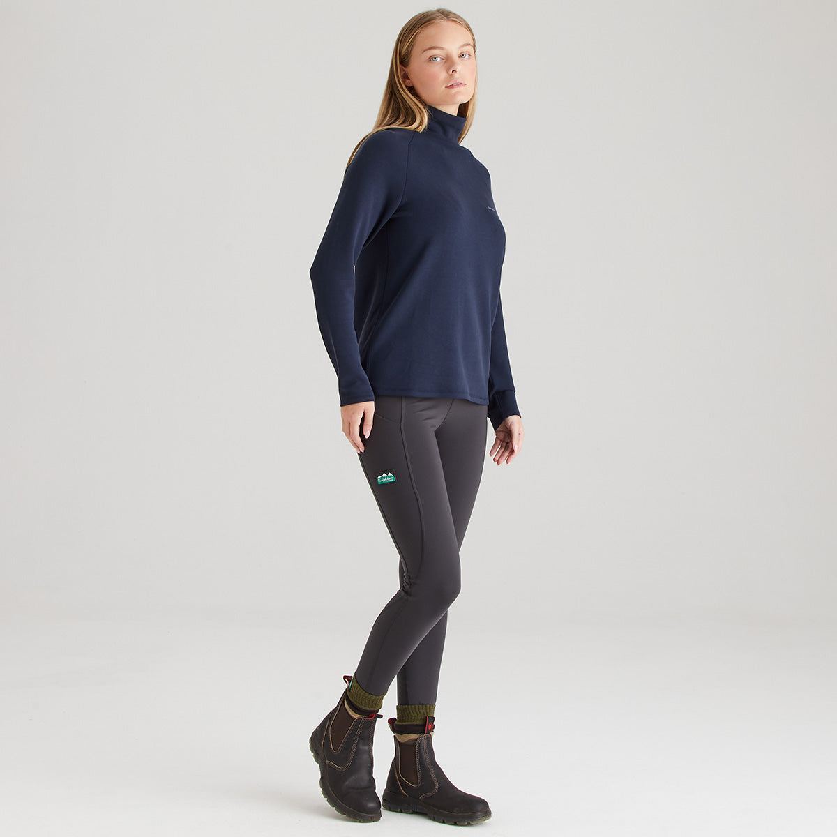 Person wearing a navy turtleneck and gray leggings on a light gray background