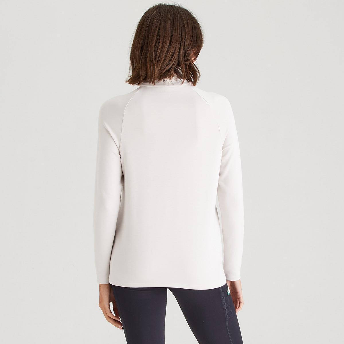 Person wearing a white long-sleeve top on a light gray background