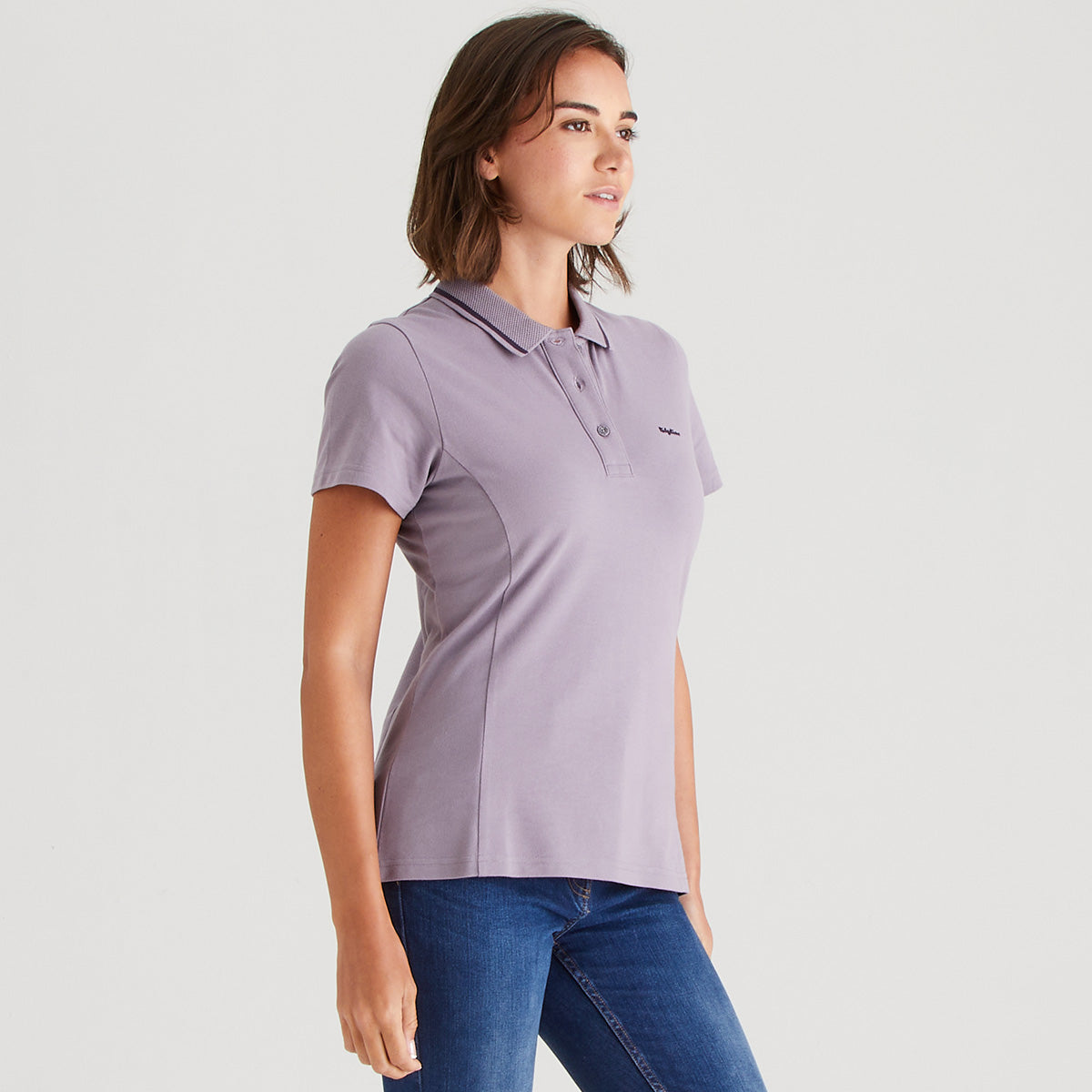 Woman wearing a light purple polo shirt with a small logo on a white background