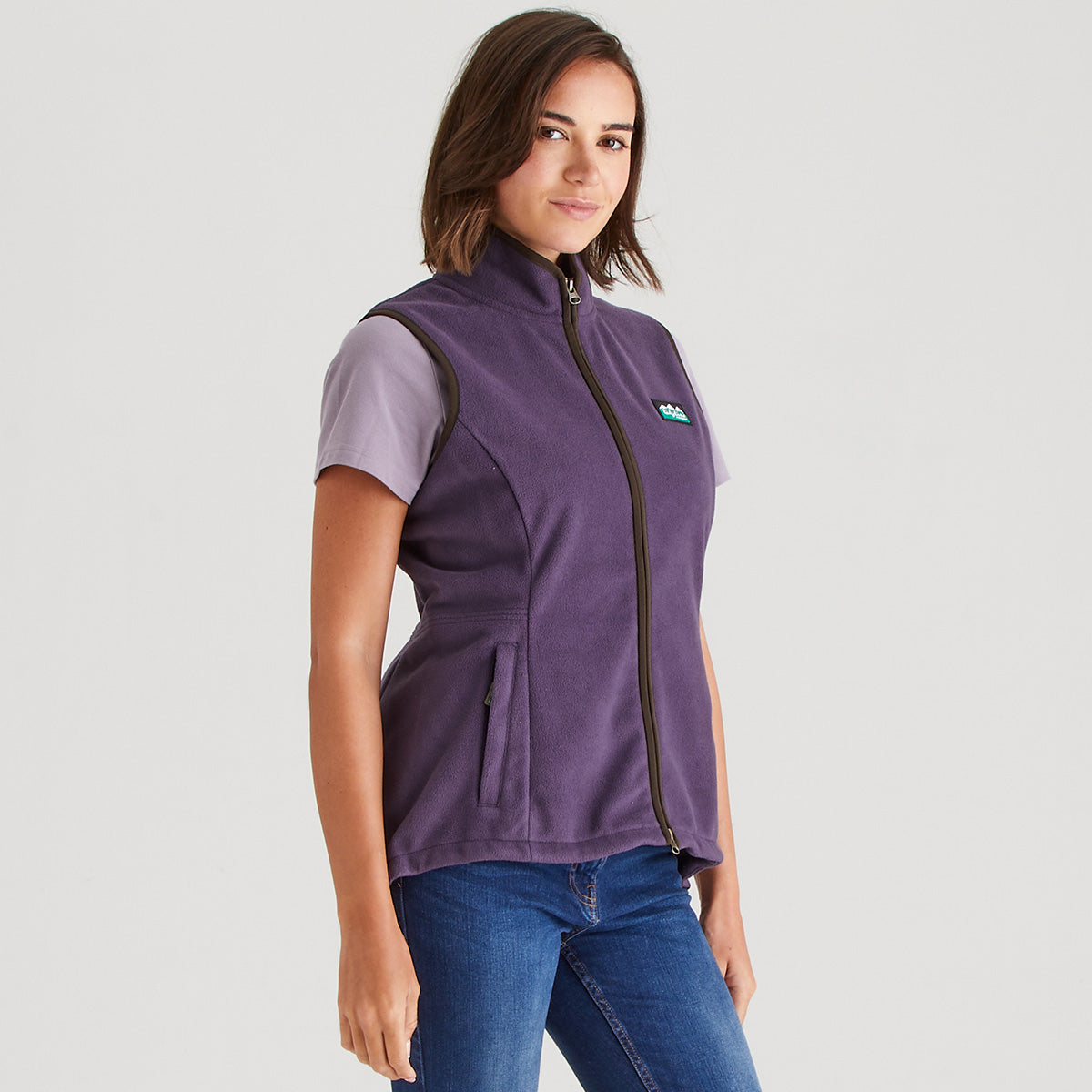Woman wearing a purple vest with a logo on a gray background