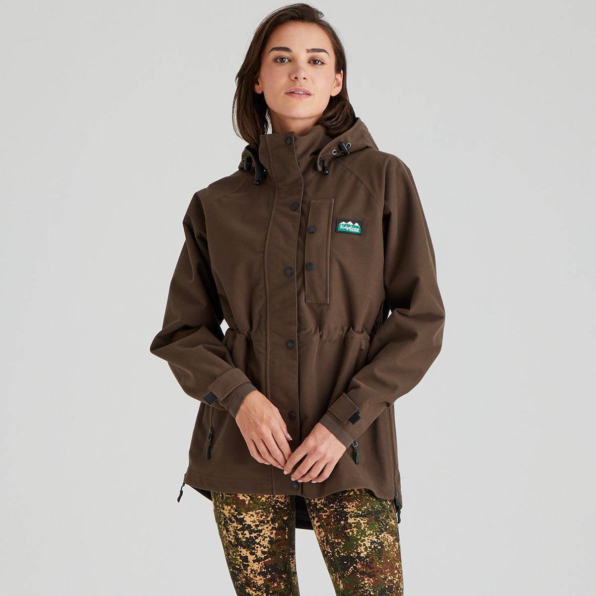 Person wearing a brown waterproof jacket with a Ridgeline Clothing logo on a grey background