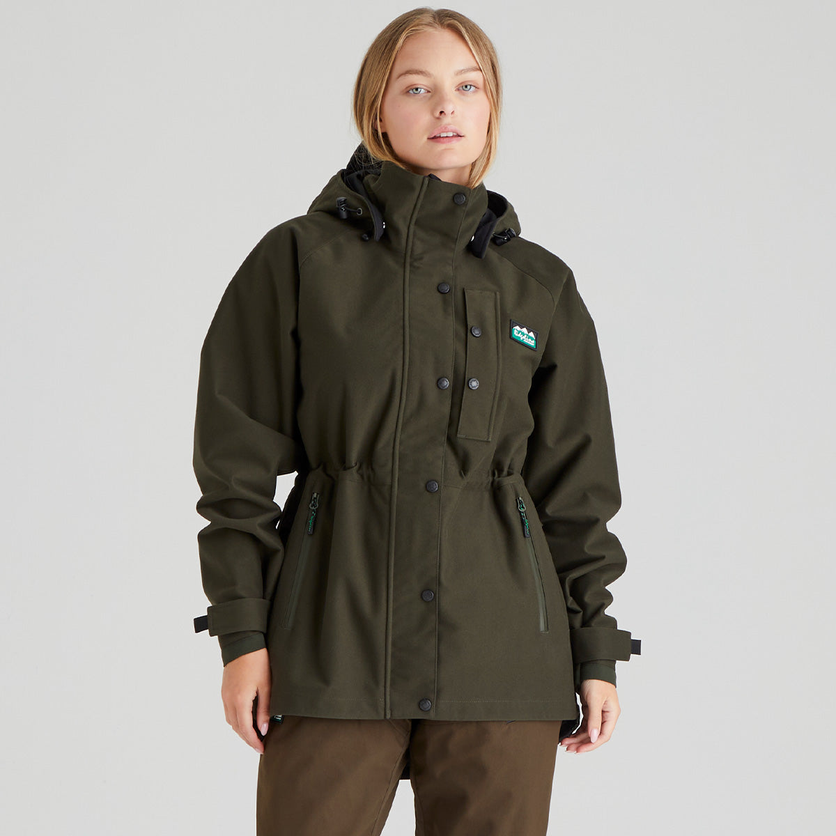 Woman wearing a green waterproof jacket with a Ridgeline Clothing brand logo on a grey background