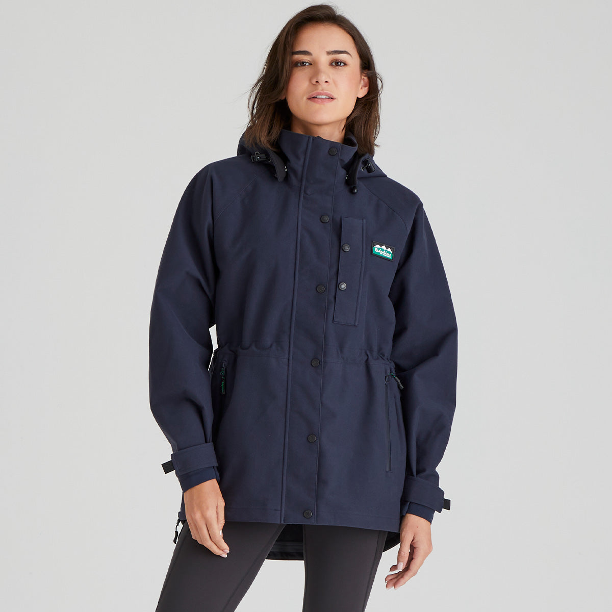Woman wearing a navy blue waterproof jacket with a Ridgeline Clothing brand logo on a grey background