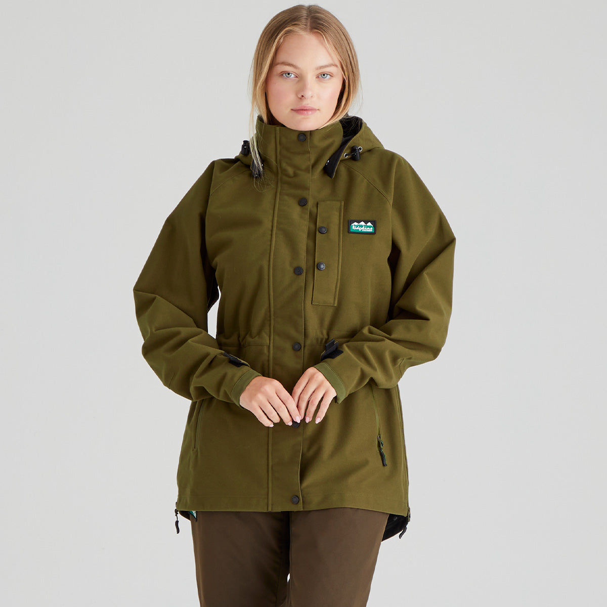 Woman wearing a brown waterproof jacket with a visible Ridgeline Clothing brand logo on a grey background