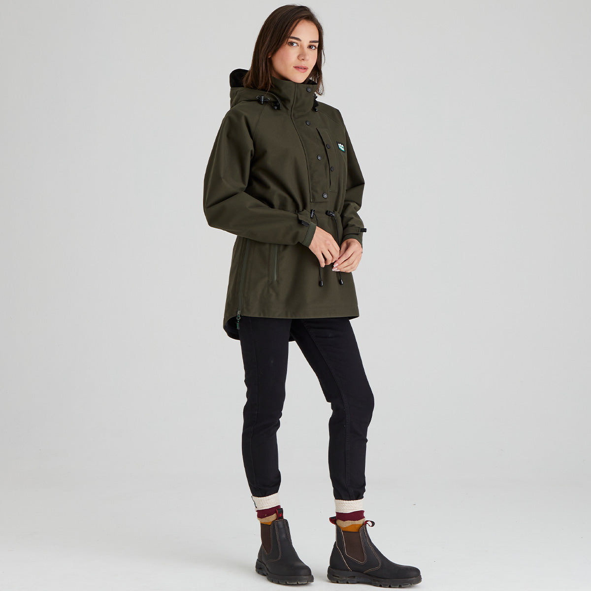 Person wearing a green waterproof raincoat on a light grey background