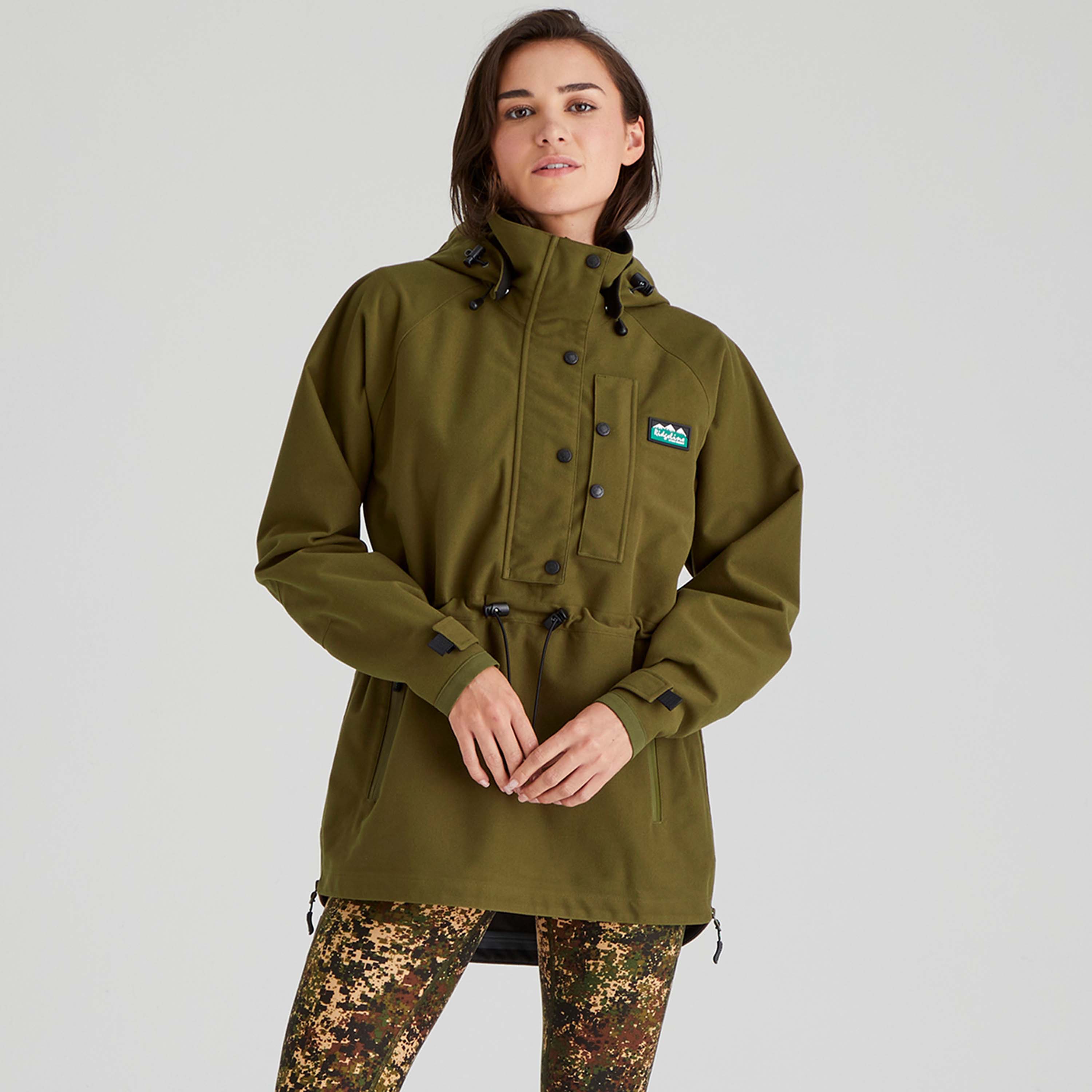 Person wearing a brown waterproof jacket with a Ridgeline Clothing brand logo on a light grey background