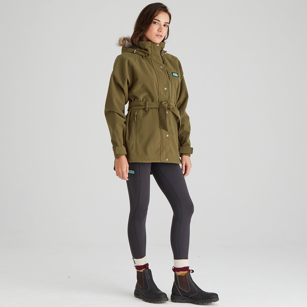 Woman wearing a green jacket with a brand logo on a white background
