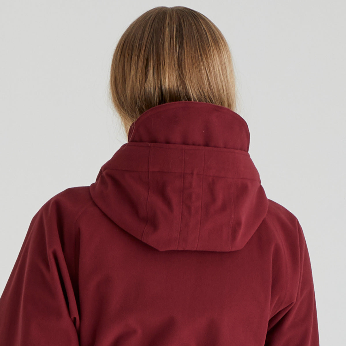 Person wearing a red hooded jacket on a plain background